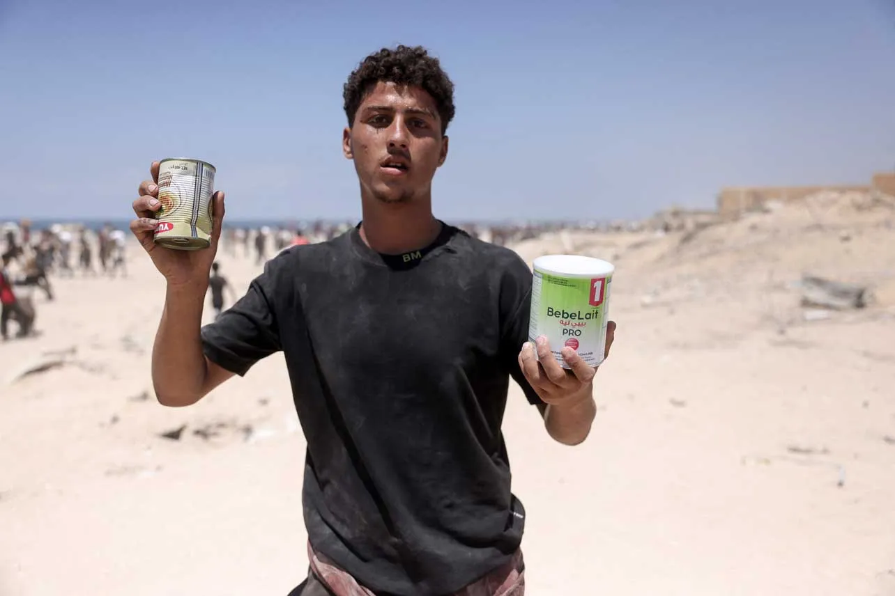 Un gazatí muestra dos latas de alimentos.