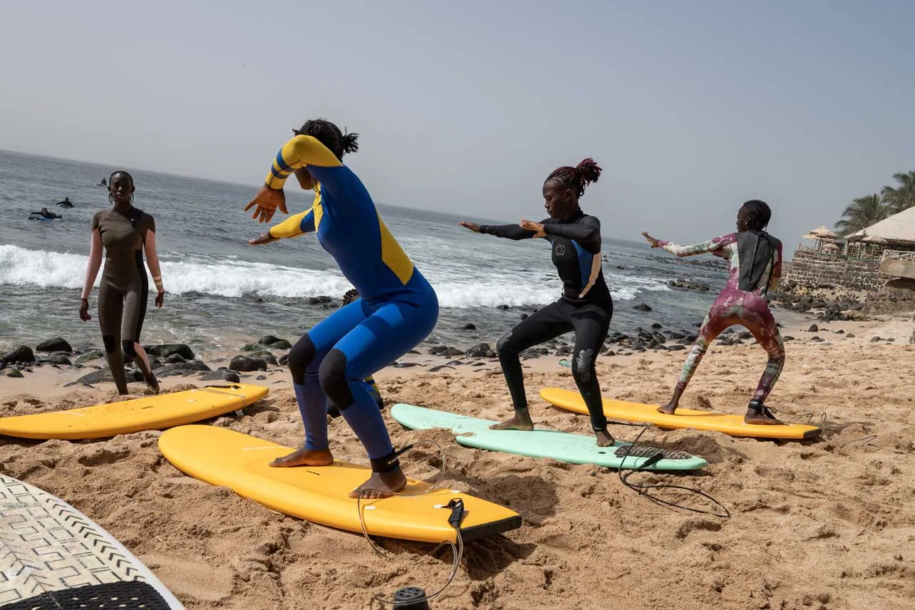 Chicas senegalesas en sus tablas de surf en la playa aprendiendo a surfear. 