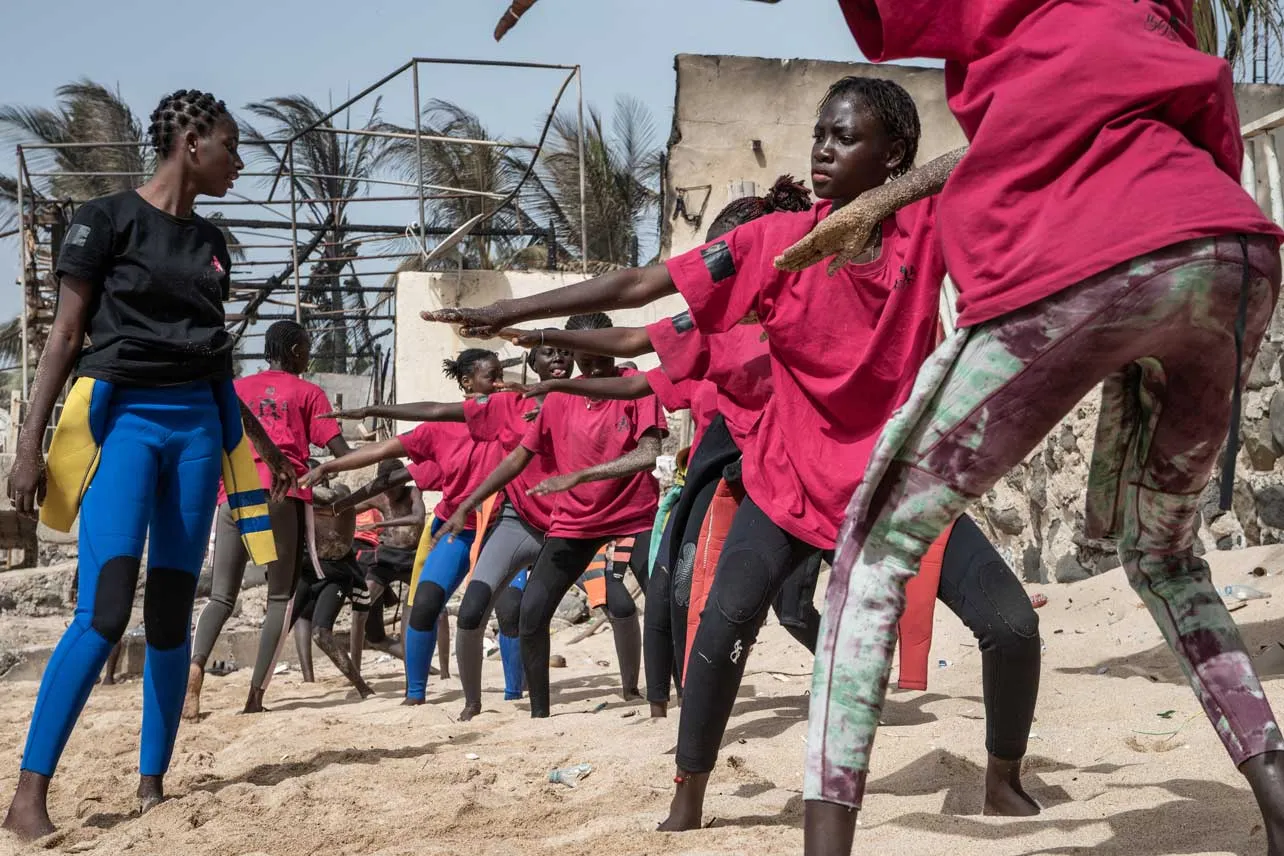 Chicas senegalesas en sus tablas de surf en la playa aprendiendo a surfear. 