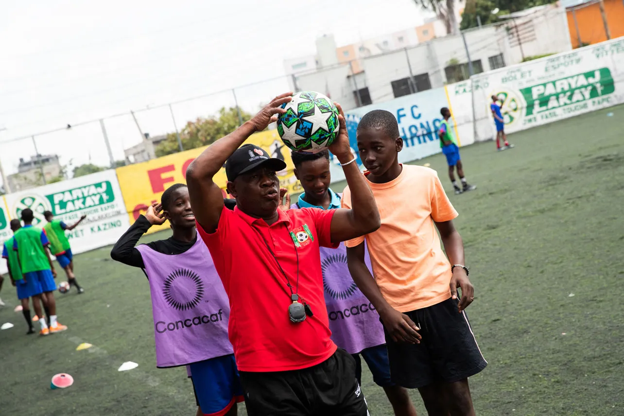 Un entrenador junto a jóvenes futbolistas en Haití.