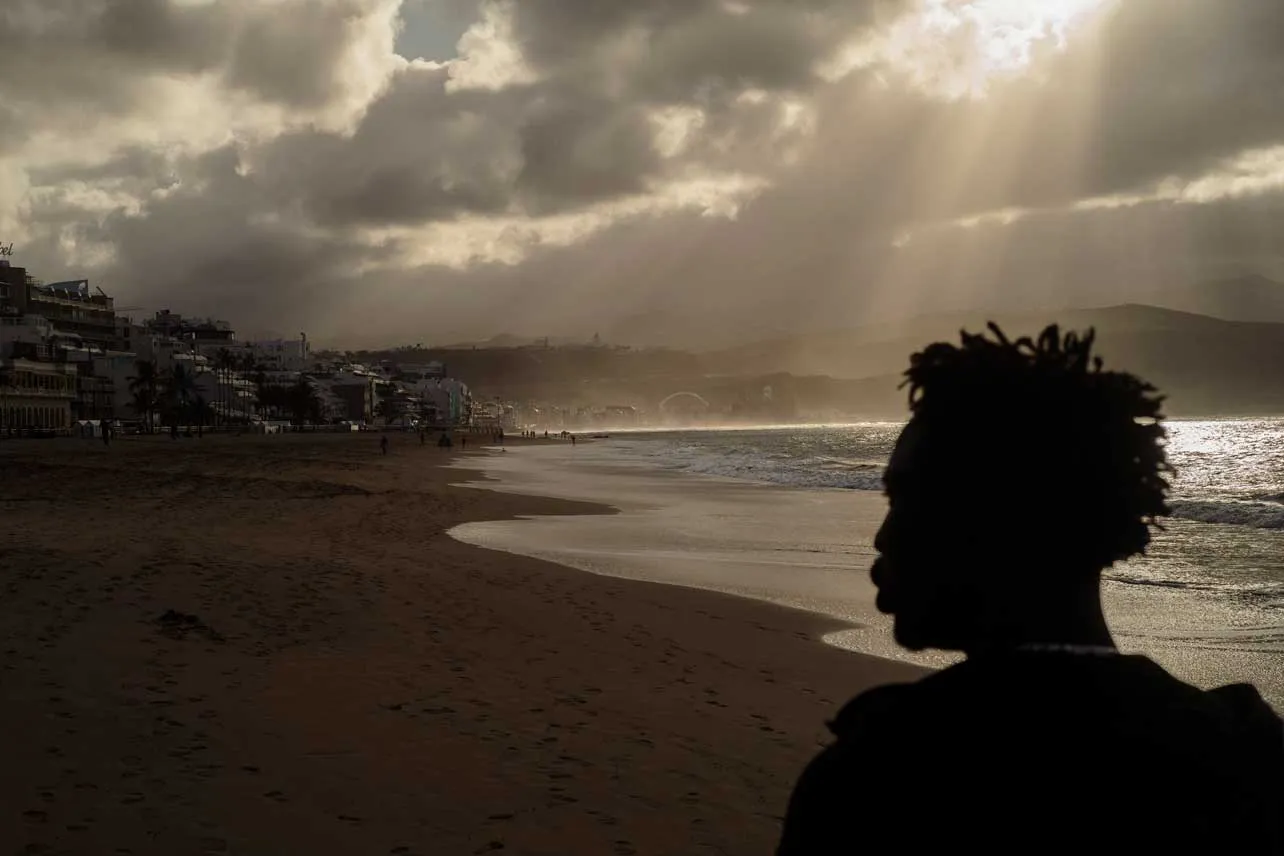 Un migrante a contraluz con la playa de Islas Canarias de fondo.