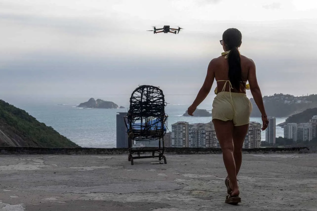 Turista camina hacia silla. Al frente se ve el dron que captura video de favelas.