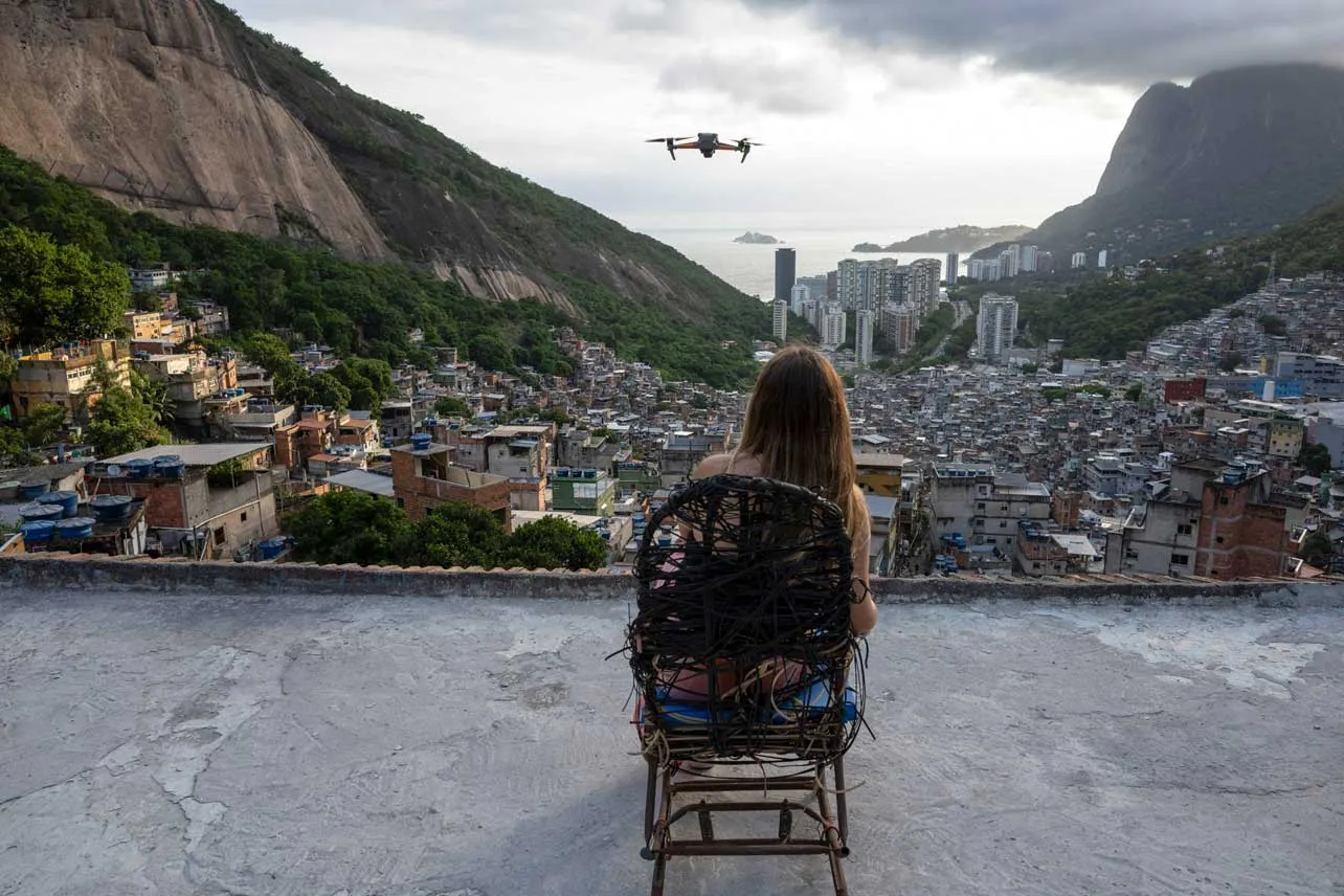 Turista sentada de espaldas mientras al frente se ve el dron que captura video de favelas.