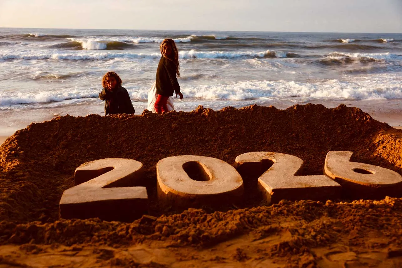 Niños en playa en Gaza con una figura de arena con el 2026.