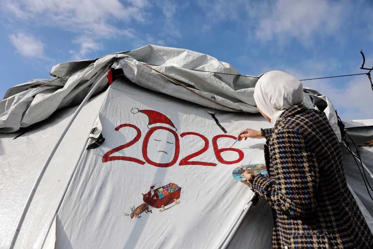 Mujer pinta el 2026 en una carpa de un campo de refugiados en Gaza.